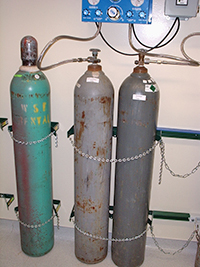 Image of CG cylinders restrained with upper and lower chains, secured to a substantial, fixed surface