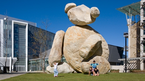 large statute of a bear made of stones on a grass lawn