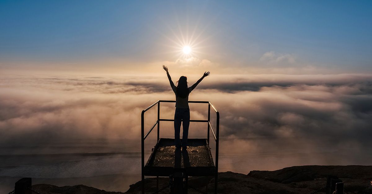 Woman silhouette looking at sunset and fog on the horizon