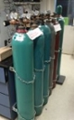 Compressed gas cylinders double-chained to wall.
