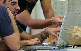 three men working at a laptop