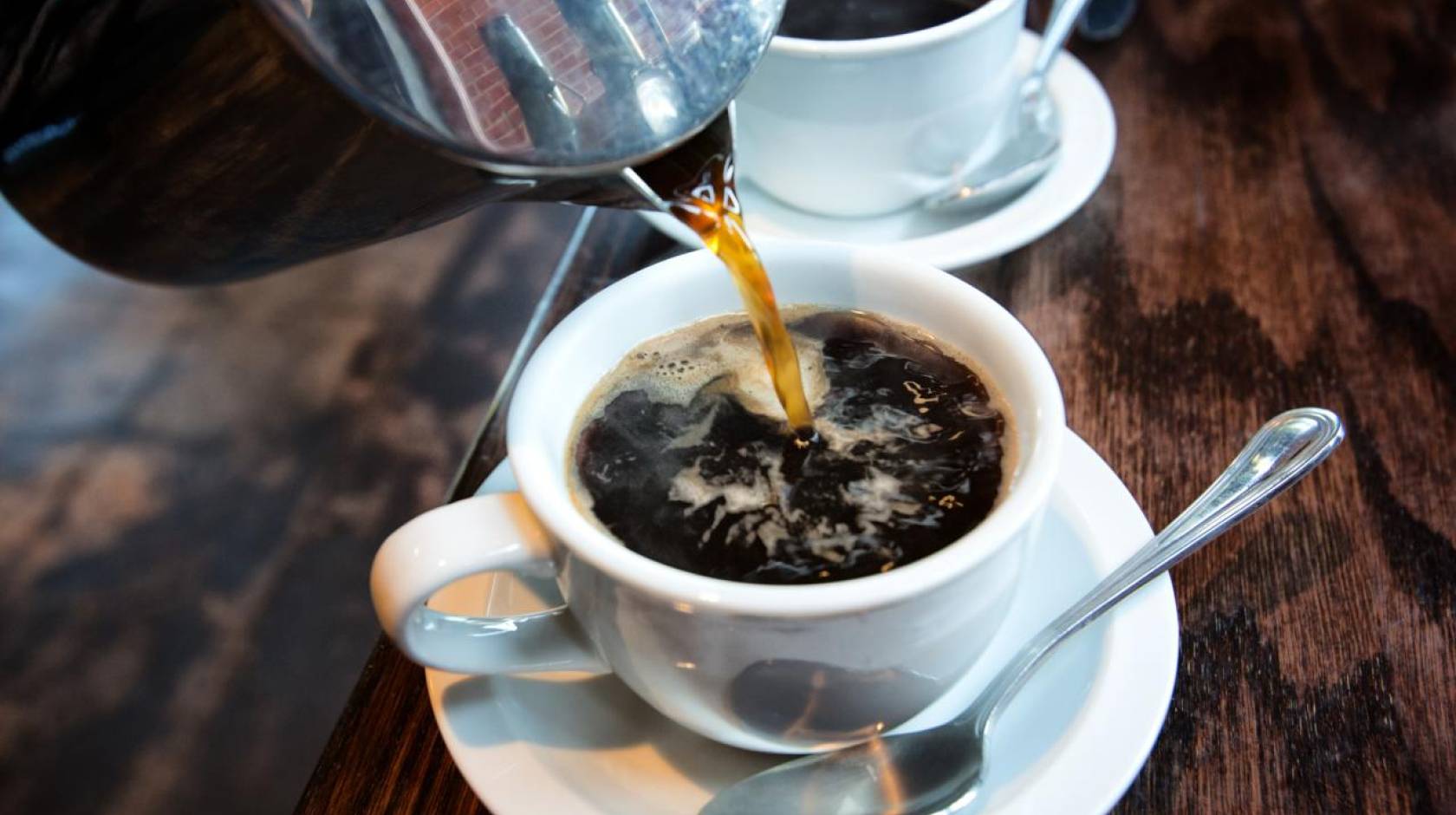 Hot coffee pouring into white mug