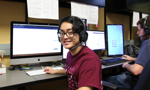 student with headset smiling at camera